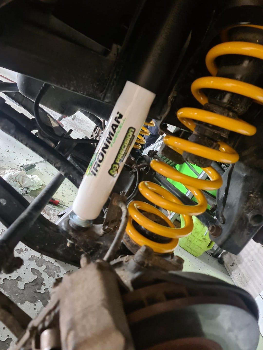 An Ironman 4x4 Foam Cell shock absorber and yellow King springs fitted under a touring four-wheel drive