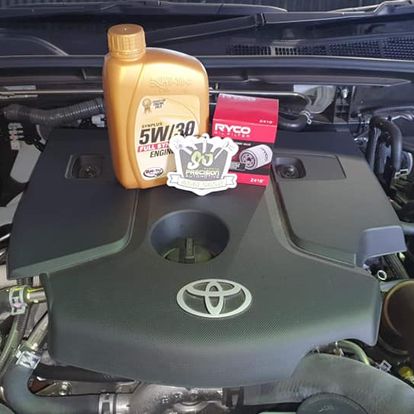 A log book service in progress on a Toyota, with the new oil and filter sitting on the engine cover