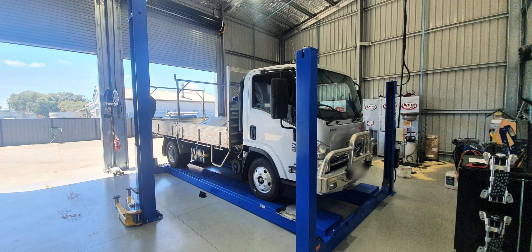 An Isuzu light truck up on a two-post hoist inside the SNJ Precision Automotive workshop